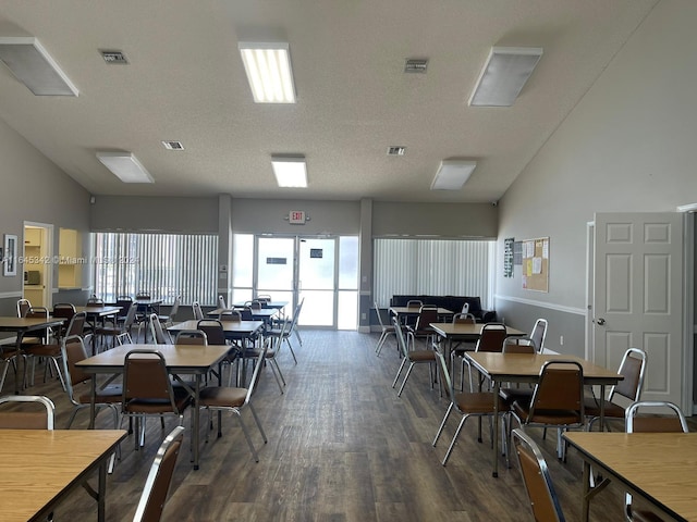 dining space featuring a textured ceiling, dark wood-type flooring, and high vaulted ceiling