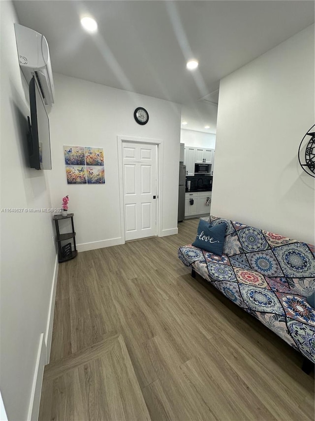 bedroom featuring stainless steel fridge and hardwood / wood-style floors