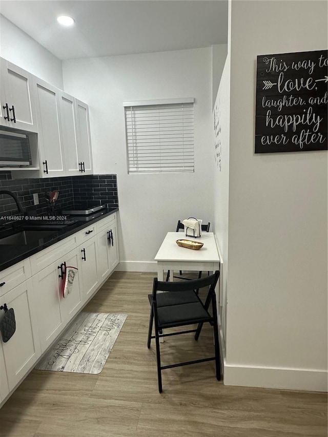 kitchen with white cabinets, light hardwood / wood-style floors, tasteful backsplash, and sink