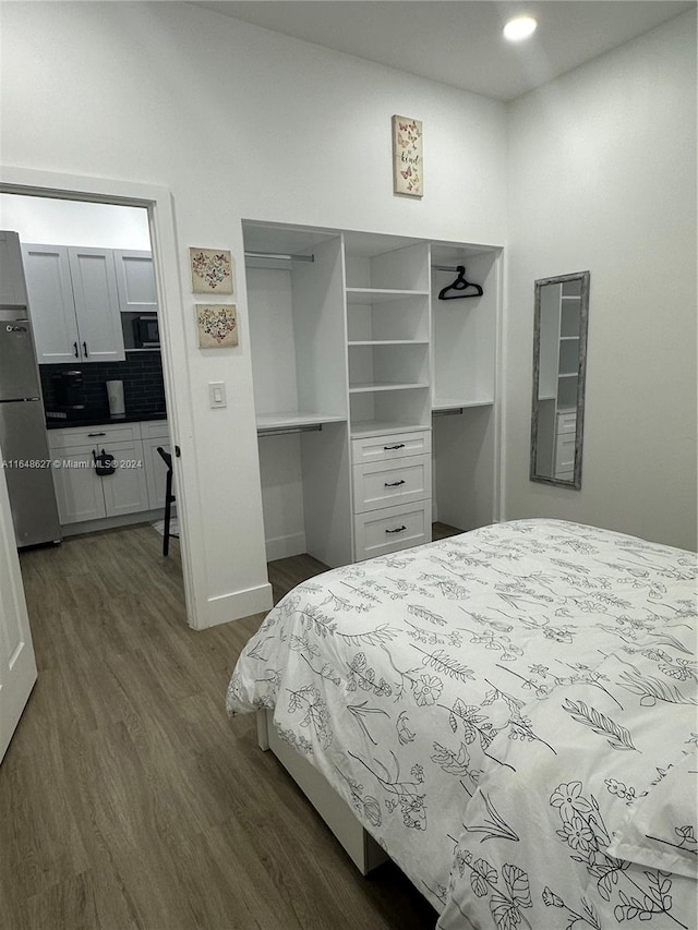 bedroom with stainless steel fridge and hardwood / wood-style floors