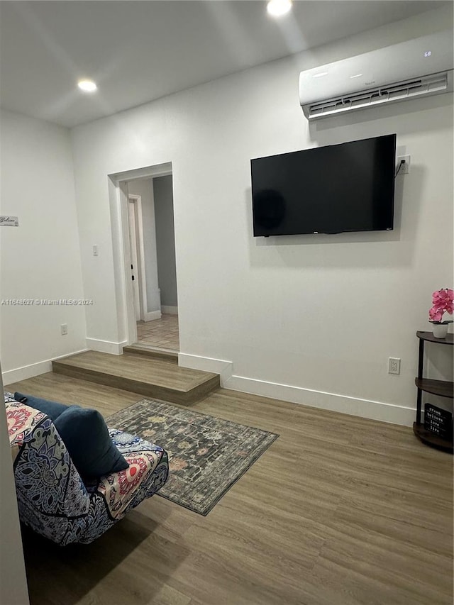 living room with an AC wall unit and hardwood / wood-style floors