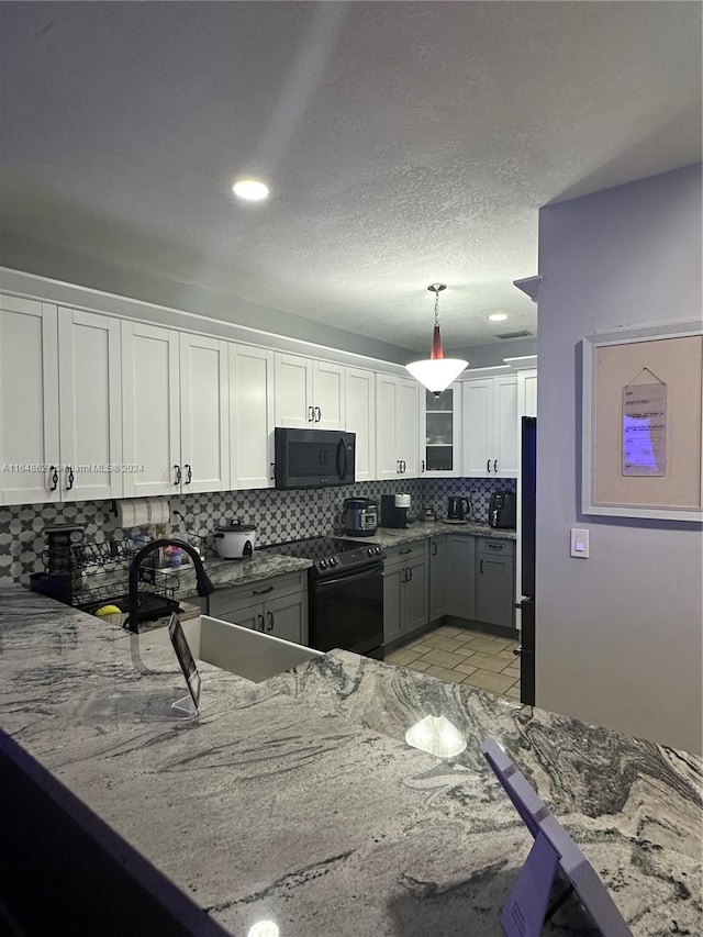 kitchen featuring decorative light fixtures, black appliances, tasteful backsplash, sink, and white cabinets