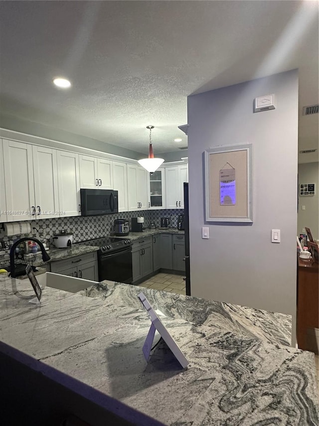 kitchen featuring pendant lighting, white cabinetry, black appliances, kitchen peninsula, and decorative backsplash