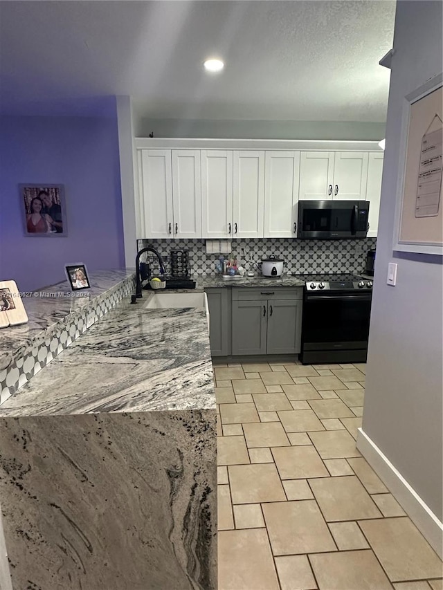 kitchen with white cabinets, electric range, light stone counters, sink, and tasteful backsplash