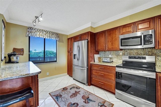 kitchen featuring appliances with stainless steel finishes, a textured ceiling, light stone counters, and light tile patterned floors