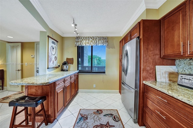 kitchen featuring stainless steel fridge, a textured ceiling, a kitchen breakfast bar, light stone counters, and light tile patterned flooring