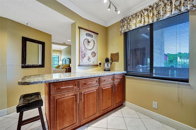 kitchen featuring crown molding, light stone counters, kitchen peninsula, and light tile patterned floors