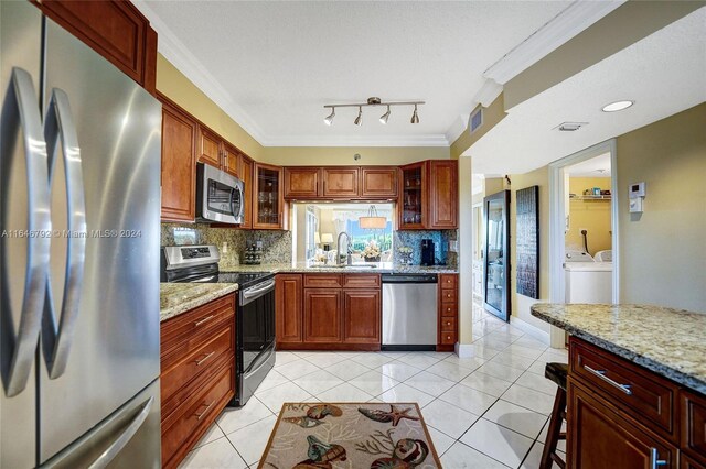 kitchen with appliances with stainless steel finishes, light stone counters, crown molding, and sink