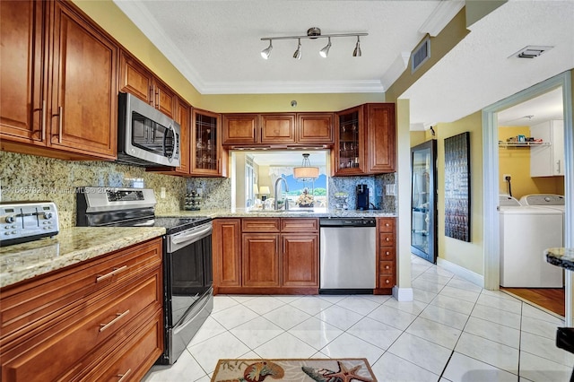 kitchen featuring separate washer and dryer, stainless steel appliances, ornamental molding, sink, and light tile patterned flooring