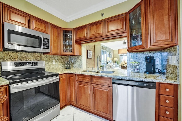 kitchen with appliances with stainless steel finishes, light stone counters, sink, and light tile patterned flooring