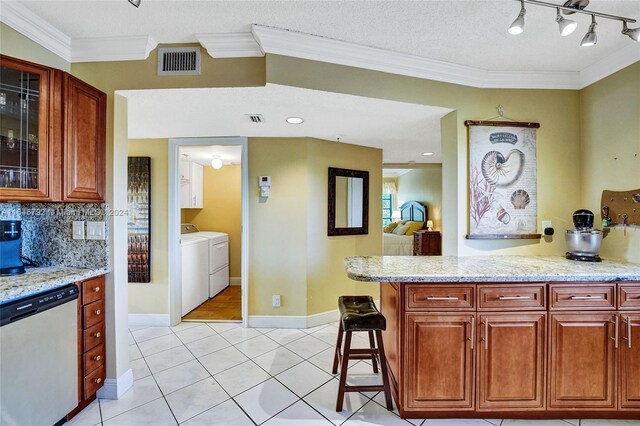 kitchen featuring backsplash, light stone countertops, independent washer and dryer, stainless steel dishwasher, and ornamental molding