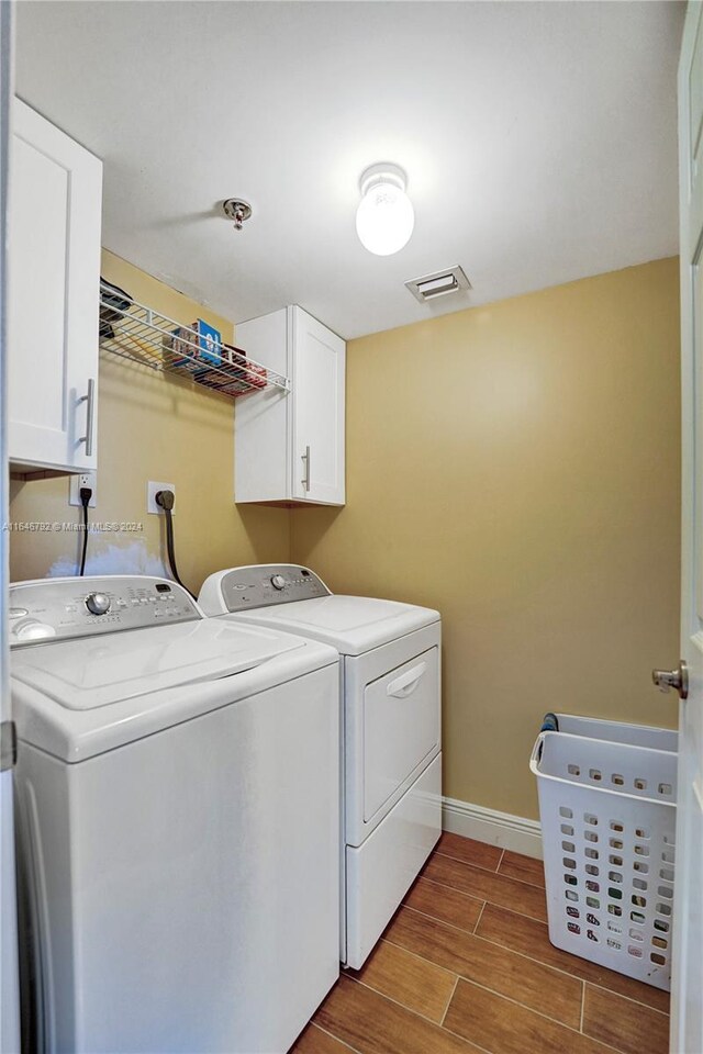 washroom with light hardwood / wood-style flooring, cabinets, and separate washer and dryer