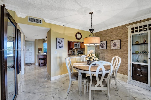 tiled dining room with sink, crown molding, and a textured ceiling