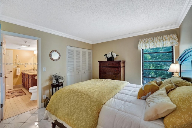 bedroom featuring a textured ceiling, ensuite bathroom, light tile patterned floors, and a closet