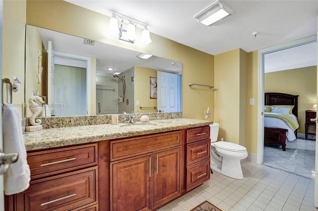 bathroom with a shower with shower door, toilet, vanity, and tile patterned floors