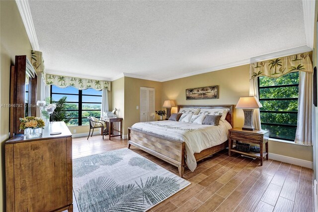 bedroom featuring a closet, dark hardwood / wood-style flooring, a textured ceiling, and ornamental molding