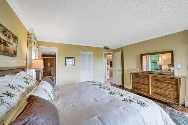 bedroom with a textured ceiling, ornamental molding, and wood-type flooring