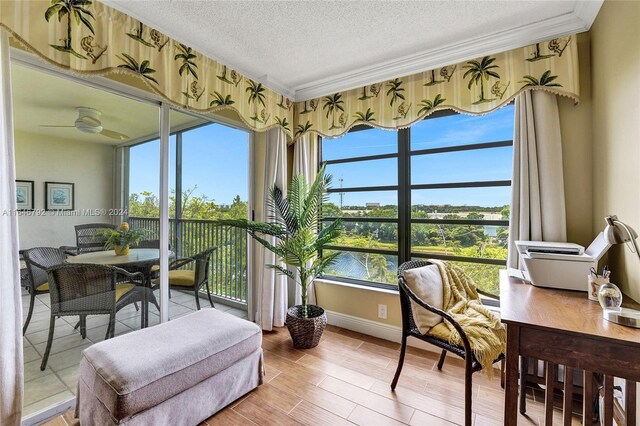 sunroom / solarium with a wealth of natural light, ceiling fan, and a water view