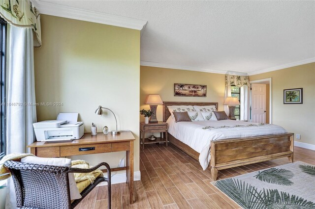 bedroom with a textured ceiling, ornamental molding, hardwood / wood-style floors, and multiple windows