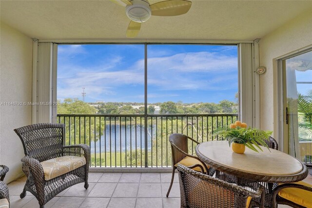 sunroom with a water view, ceiling fan, and a wealth of natural light