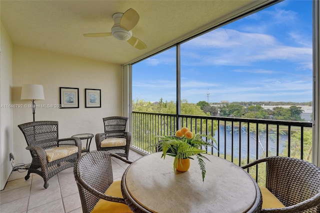 sunroom featuring ceiling fan and a water view