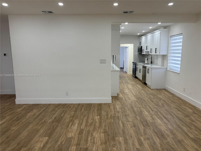 kitchen featuring white cabinetry, backsplash, wood-type flooring, and stainless steel appliances