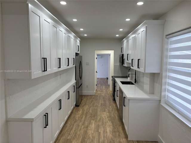 kitchen featuring white cabinetry, appliances with stainless steel finishes, sink, and wood-type flooring