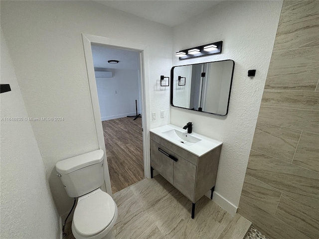 bathroom with an AC wall unit, toilet, vanity, and wood-type flooring