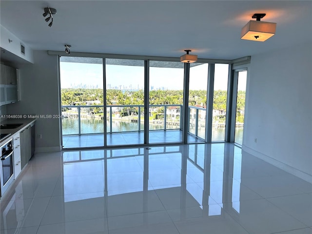 tiled spare room with sink, expansive windows, and a water view