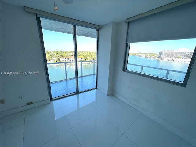 empty room featuring plenty of natural light, a water view, and light tile patterned floors