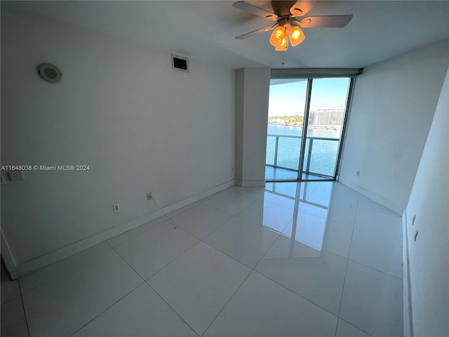 spare room featuring a wall of windows, ceiling fan, and light tile patterned floors