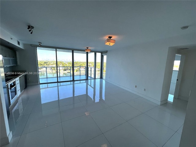 empty room featuring tile patterned flooring and a wall of windows