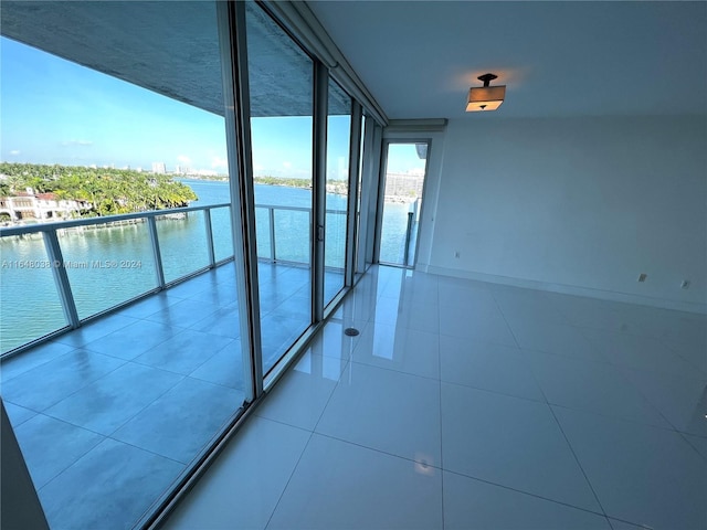 tiled empty room featuring a wall of windows and a water view