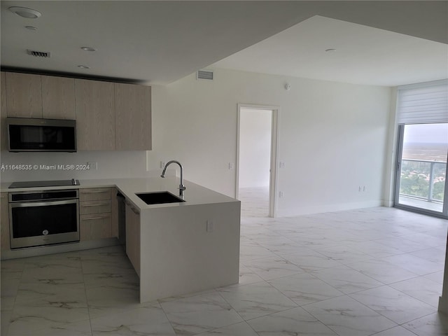 kitchen featuring appliances with stainless steel finishes, sink, and light brown cabinets