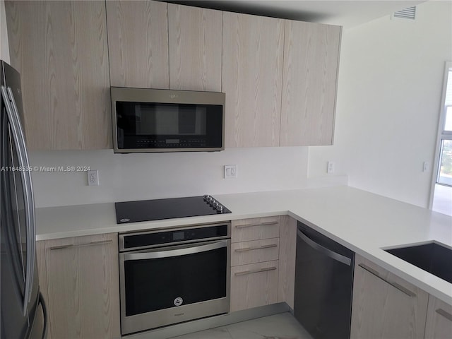 kitchen featuring light brown cabinetry, sink, and appliances with stainless steel finishes