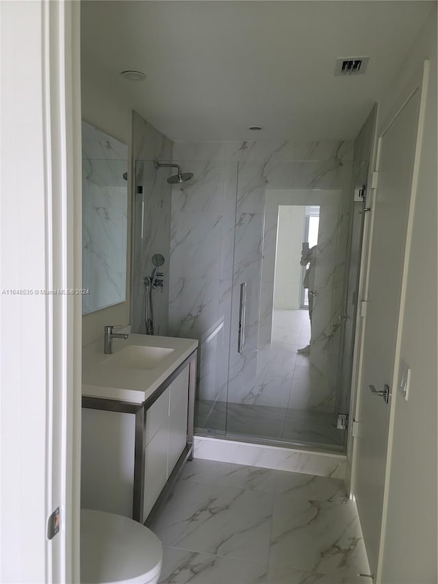 bathroom featuring vanity, a shower with shower door, and toilet