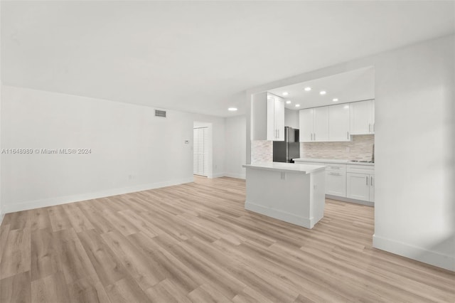 kitchen with stainless steel fridge, light hardwood / wood-style flooring, white cabinetry, and tasteful backsplash