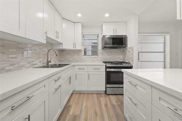 kitchen with light hardwood / wood-style floors, sink, white cabinetry, and stainless steel appliances