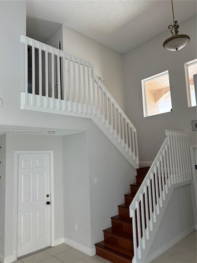 staircase with tile patterned flooring and a textured ceiling