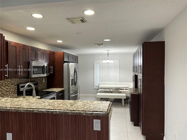 kitchen featuring decorative backsplash, light tile patterned floors, decorative light fixtures, kitchen peninsula, and stainless steel appliances