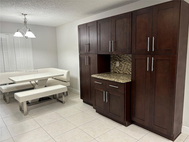 kitchen featuring light tile patterned flooring, a textured ceiling, backsplash, and pendant lighting