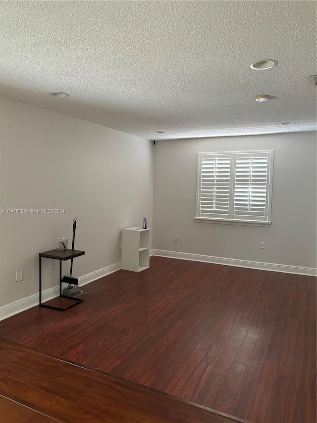 empty room with a textured ceiling and dark wood-type flooring