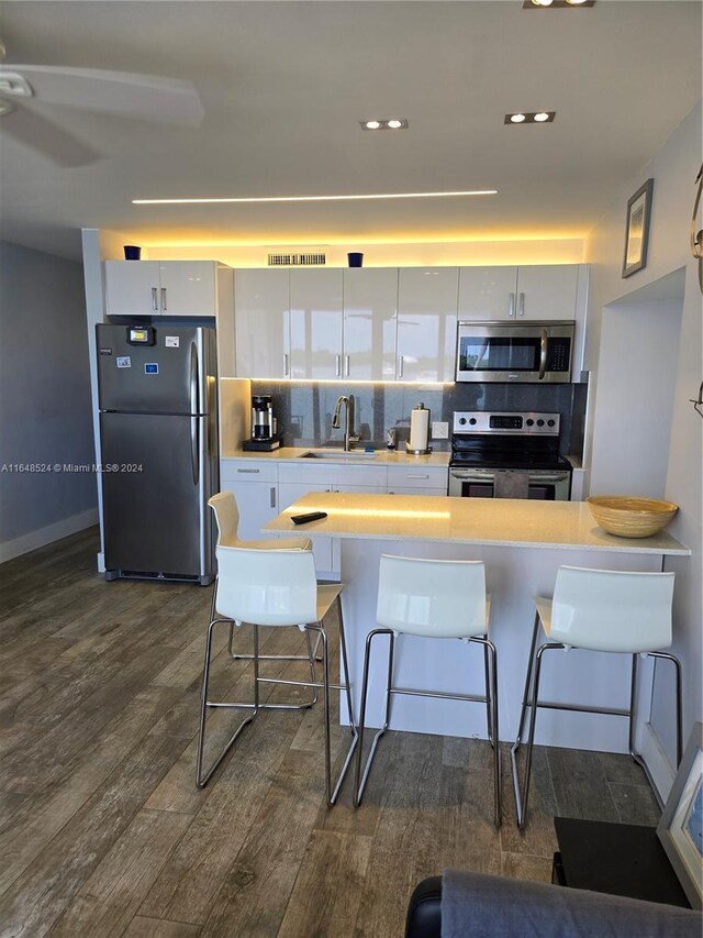 kitchen featuring sink, decorative backsplash, dark hardwood / wood-style floors, stainless steel appliances, and white cabinets