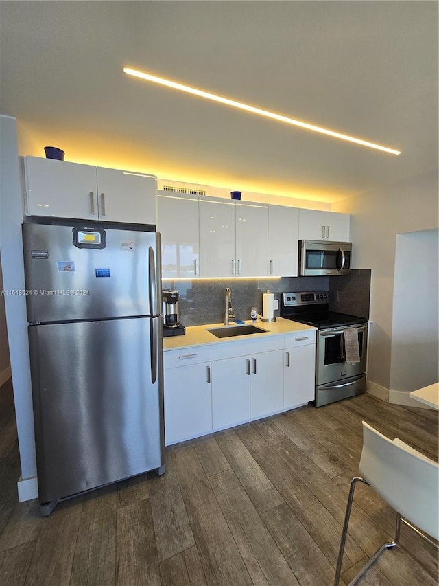 kitchen with a sink, white cabinets, light countertops, appliances with stainless steel finishes, and dark wood finished floors