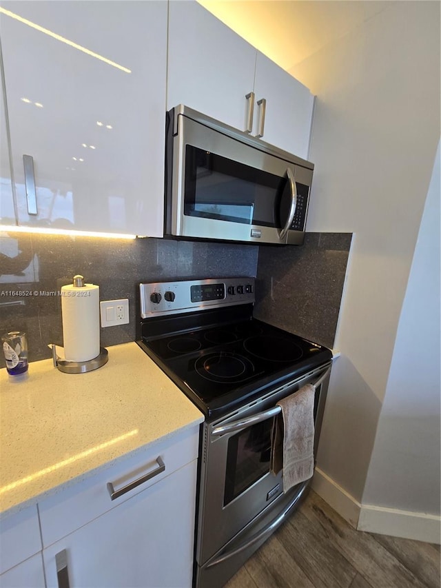 kitchen featuring stainless steel appliances, dark wood-style flooring, white cabinetry, and tasteful backsplash