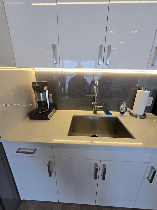 room details featuring white cabinetry, a sink, and decorative backsplash