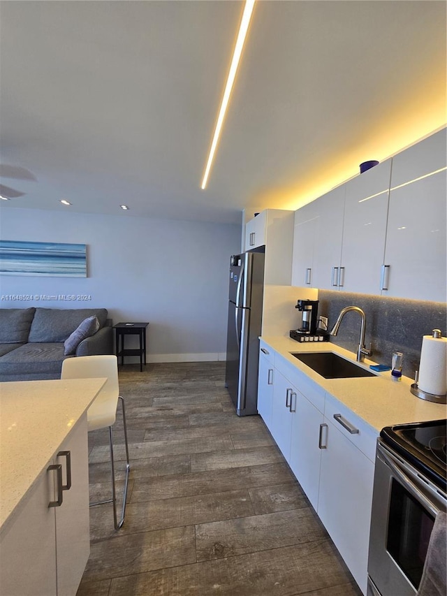 kitchen with appliances with stainless steel finishes, light countertops, a sink, and white cabinetry