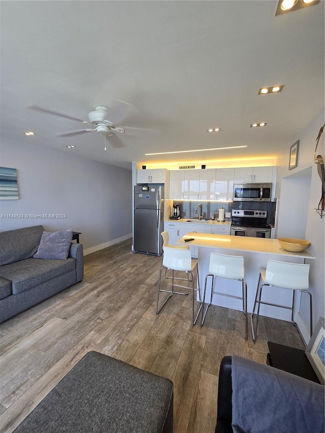 kitchen with appliances with stainless steel finishes, open floor plan, white cabinets, and a breakfast bar area