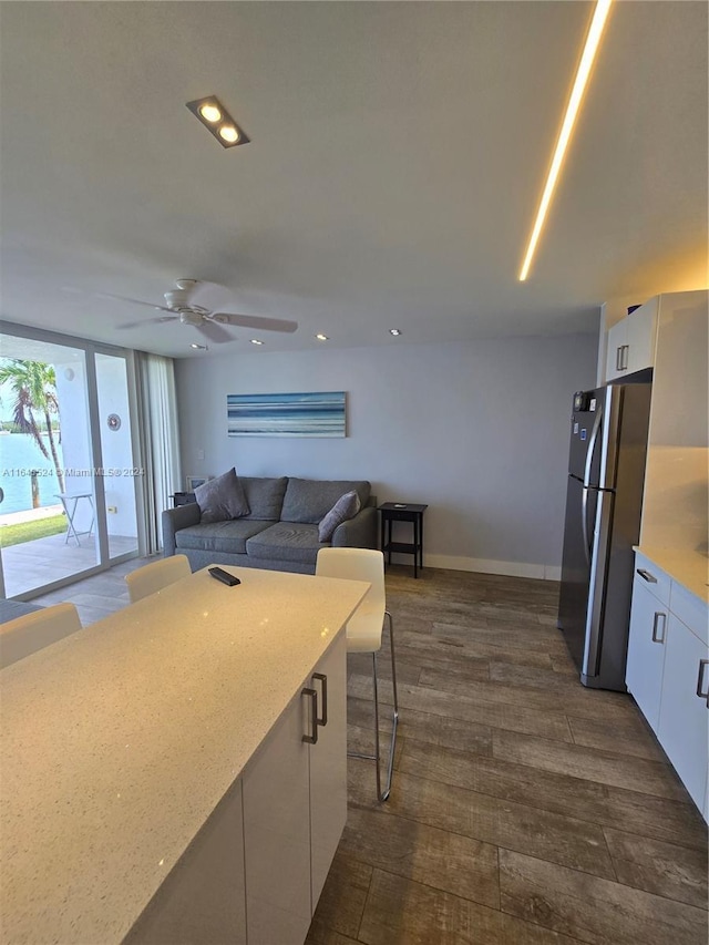 kitchen with light countertops, freestanding refrigerator, open floor plan, and white cabinets