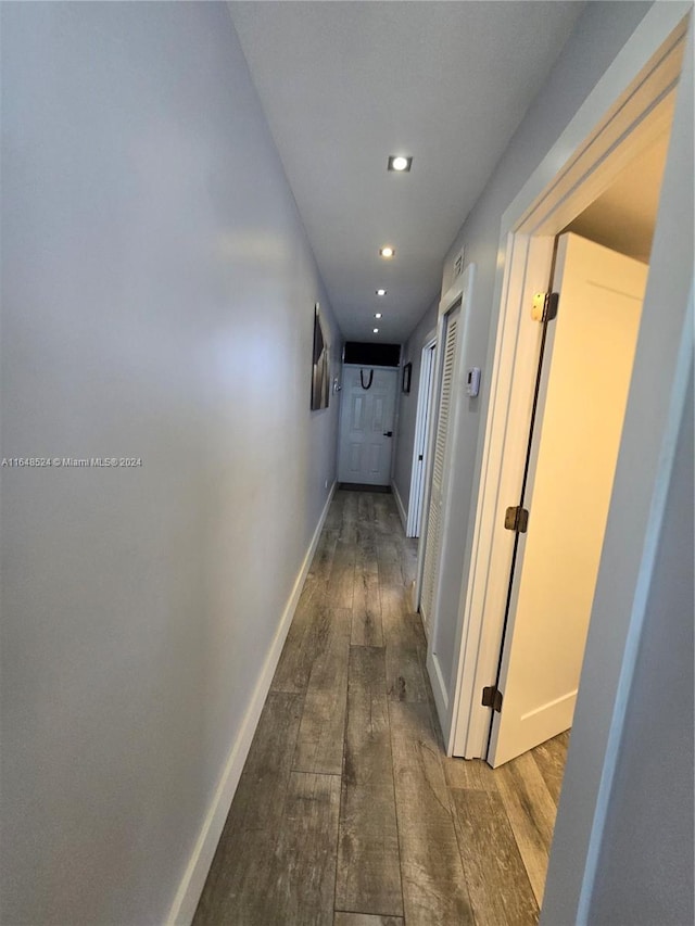 hall featuring baseboards, wood finished floors, and recessed lighting